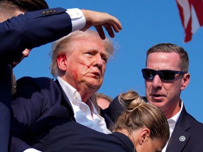 Дональд Трамп окружен агентами Секретной службы, когда он покидает сцену на предвыборном митинге в Батлере после покушения, Пенсильвания, 13 июля. Фото: Evan Vucci / AP Дональд Трамп окружен агентами Секретной службы, когда он покидает сцену на предвыборном митинге в Батлере после покушения, Пенсильвания, 13 июля. Фото: Evan Vucci / AP